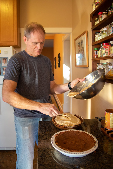 Gawel spoons whip cream into a pie pan.