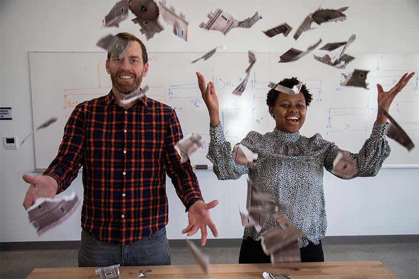 Jeff Walters and Angela Kitali throwing pieces of a cardboard castle into the air.