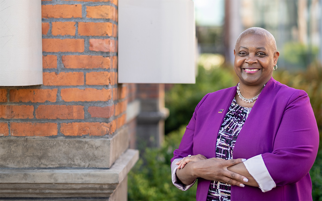 UW Tacoma Chancellor Sheila Edwards Lange near a brick wall with green plants in background