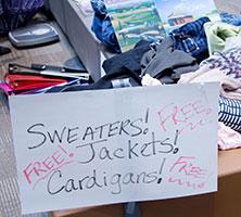 Handwritten sign at UW Tacoma swap meet reading "Sweaters! Jackets! Cardigans! Free!"