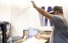 Facilities staff member installing plexiglass shields at the UW Tacoma Office of Admissions front desk.