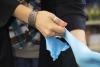 The hands of Dr. Anna Groat Carmona, shown pulling on blue latex gloves.